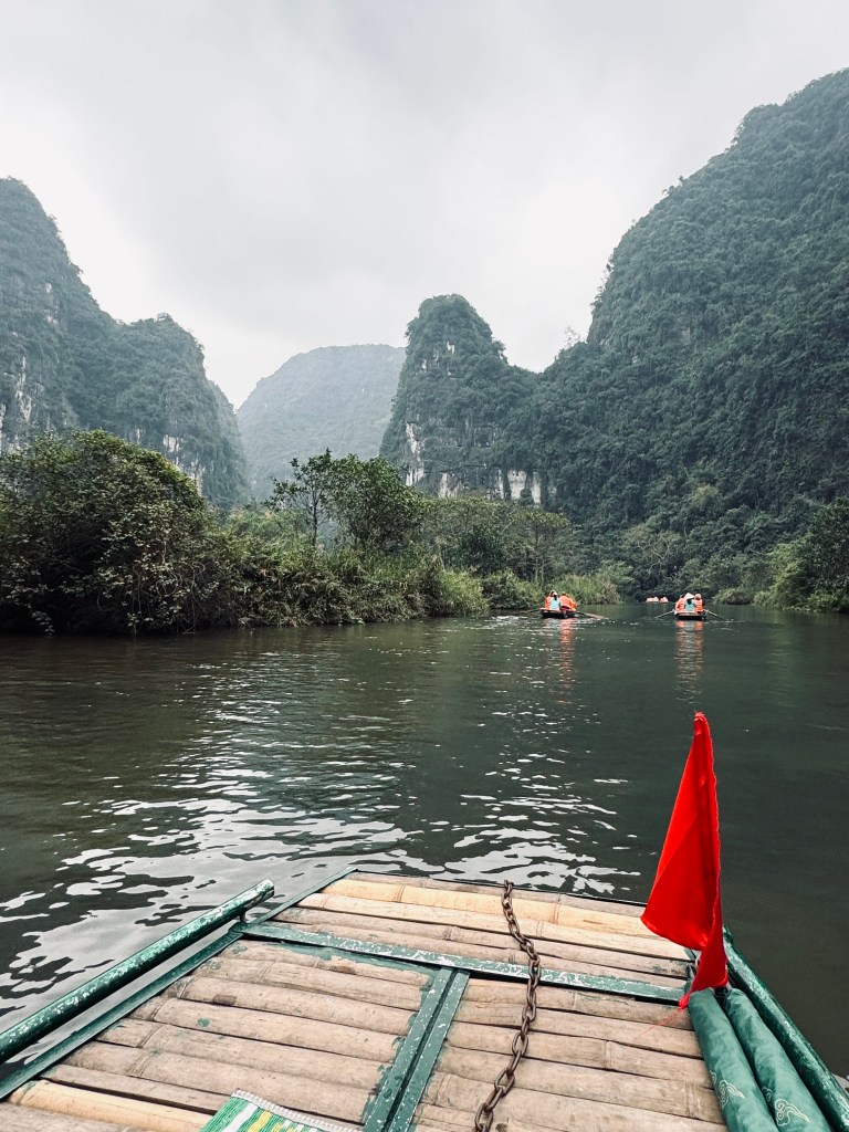 Boat on Trang An boat ride with mountains in background in Ninh Binh, Vietnam
