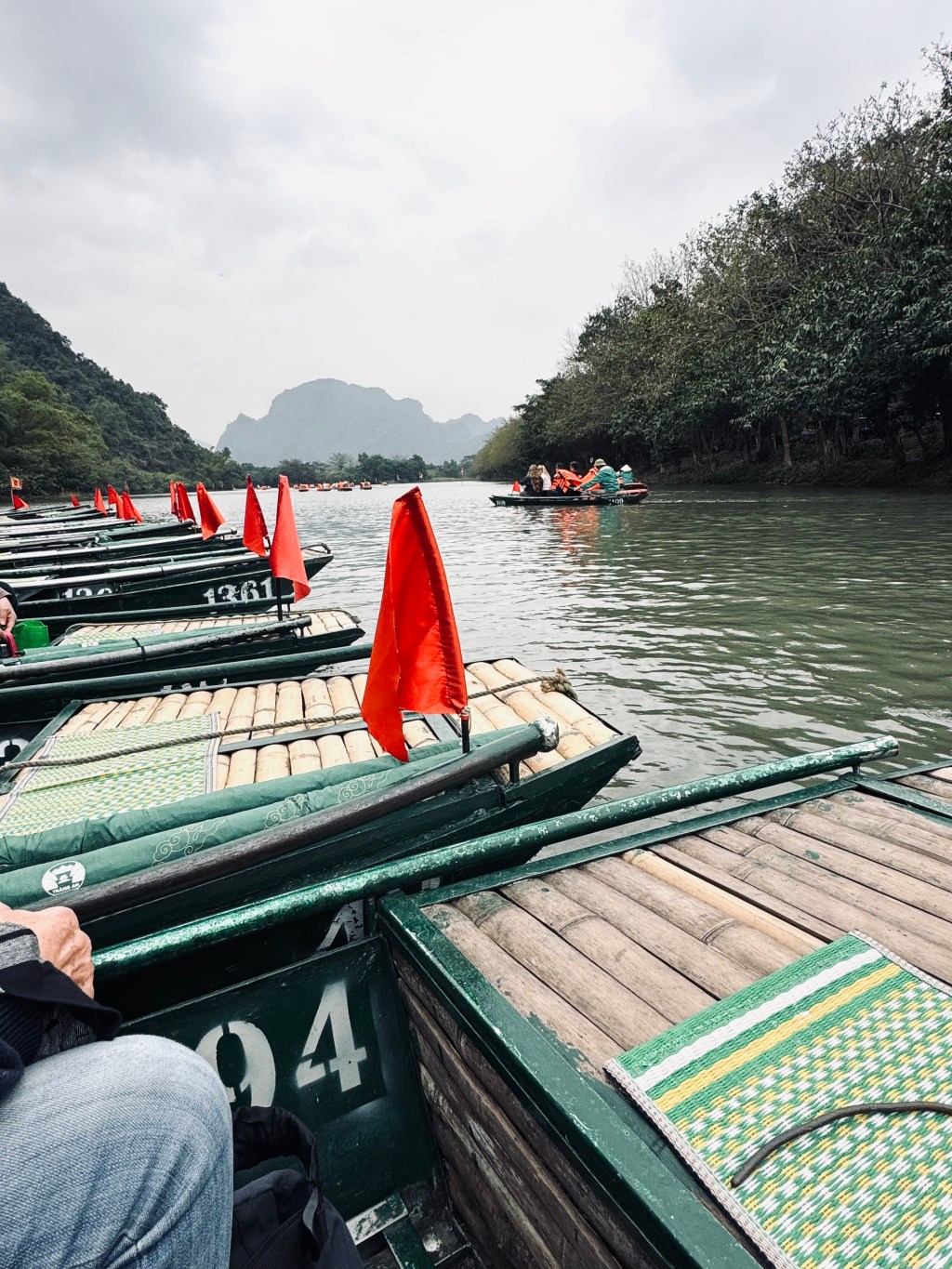 Boats on Trang An boat ride with mountains in background in Ninh Binh, Vietnam