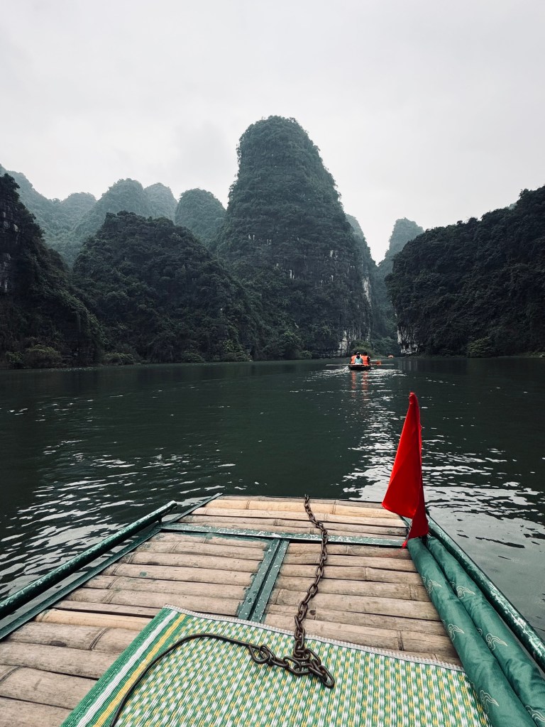 Boat on Trang An boat ride with mountains in background in Ninh Binh, Vietnam