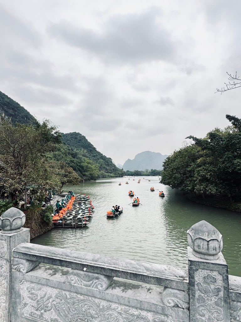 Boats on Trang An boat ride with mountains in background in Ninh Binh, Vietnam