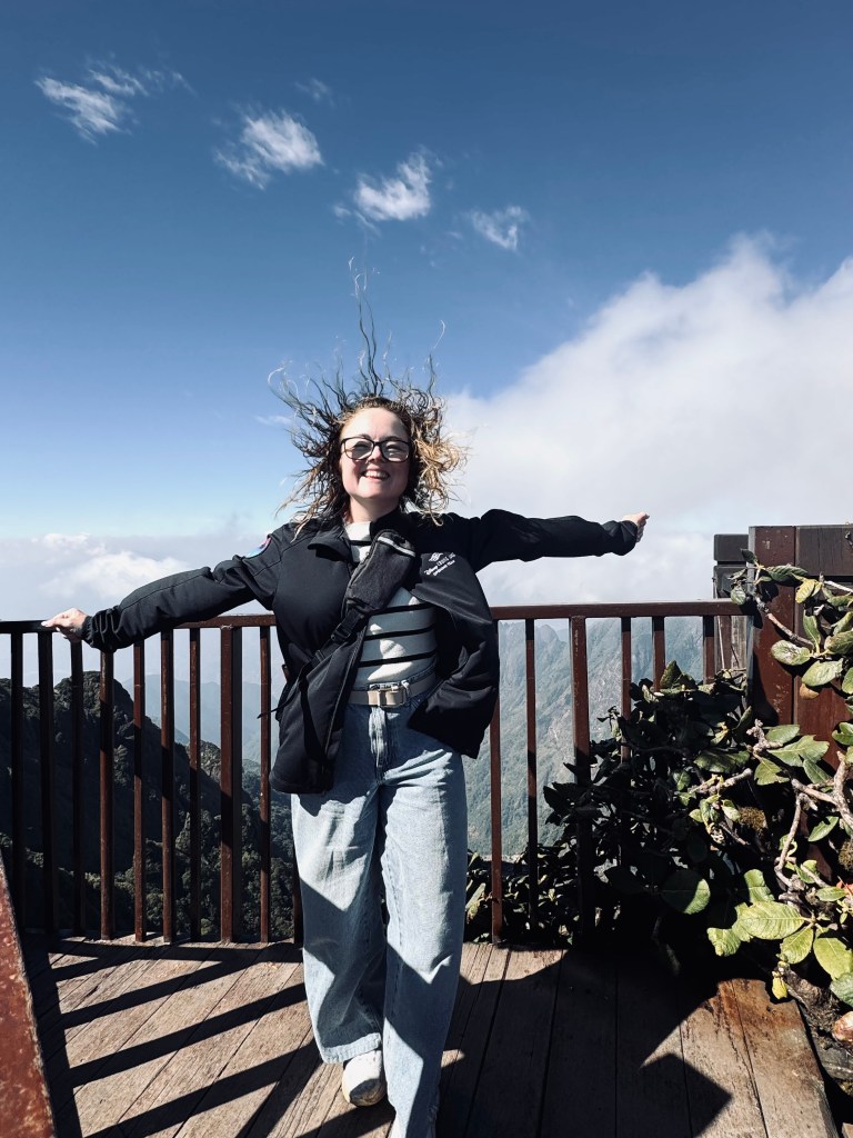 Girl posing with wind blowing her hair at the peak of Fansipan Mountain in Sapa, Vietnam