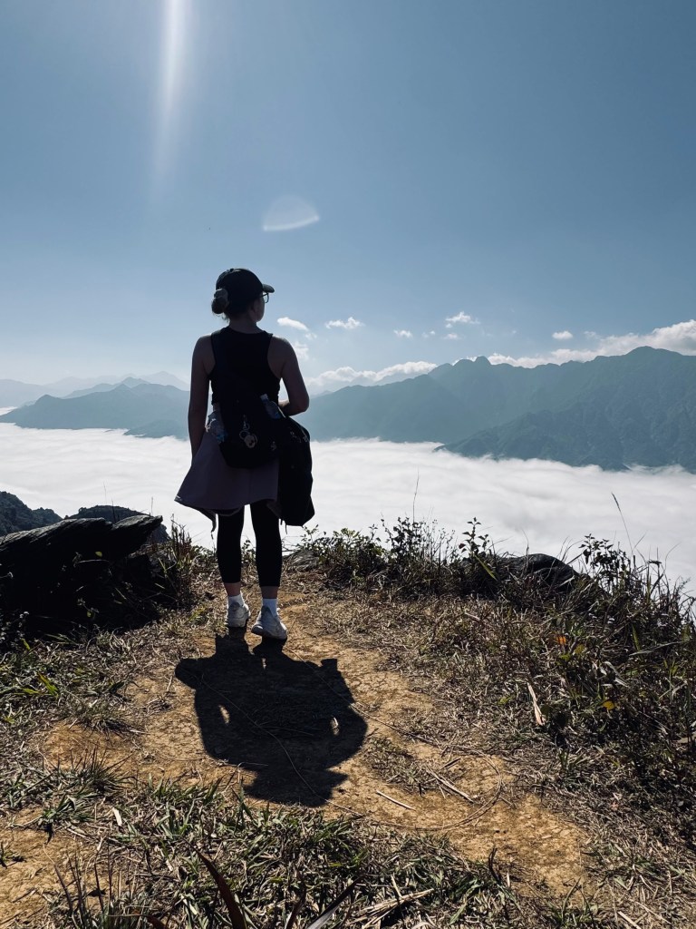 Girl looking out at mountains above the clouds on a trekking tour in Sapa, Vietnam