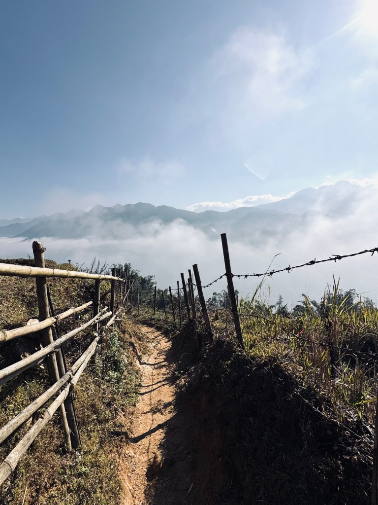 Dirt path with fence and mountains in background on a trekking tour in Sapa, Vietnam