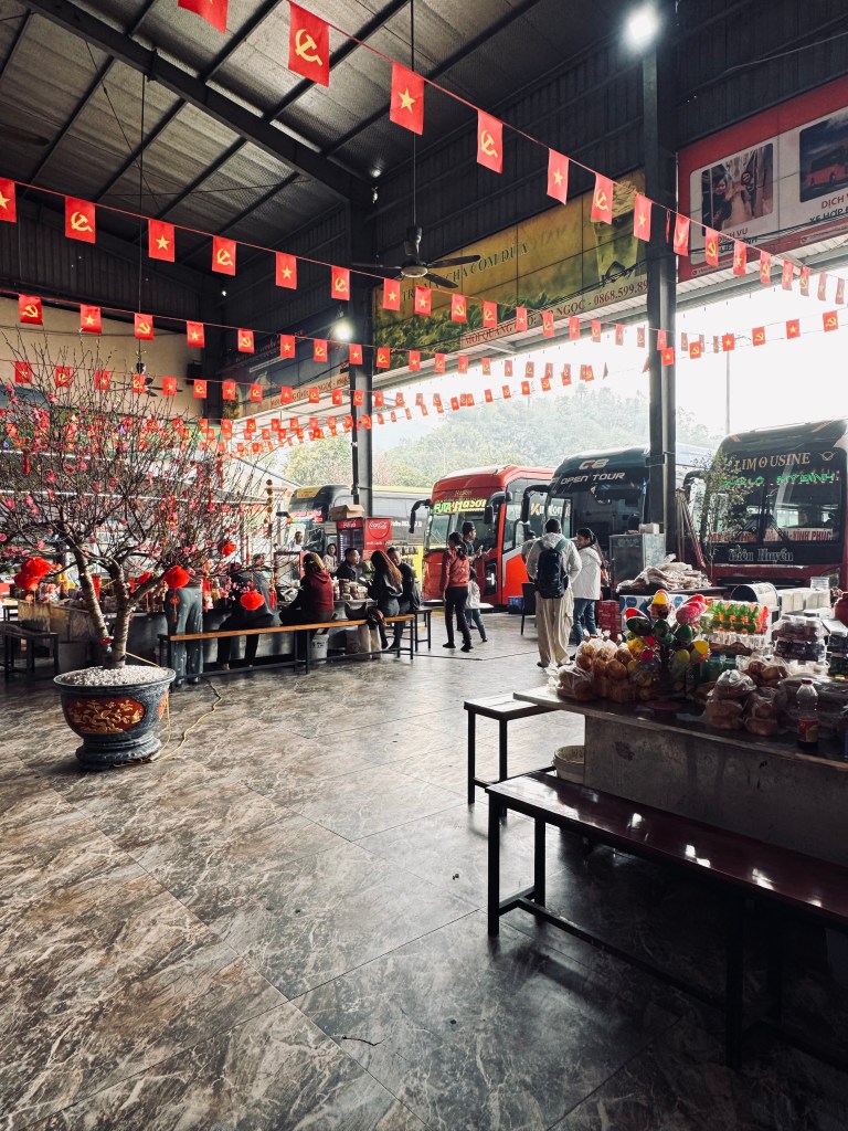 Bus rest stop in Vietnam with Vietnamese flags and buses in background